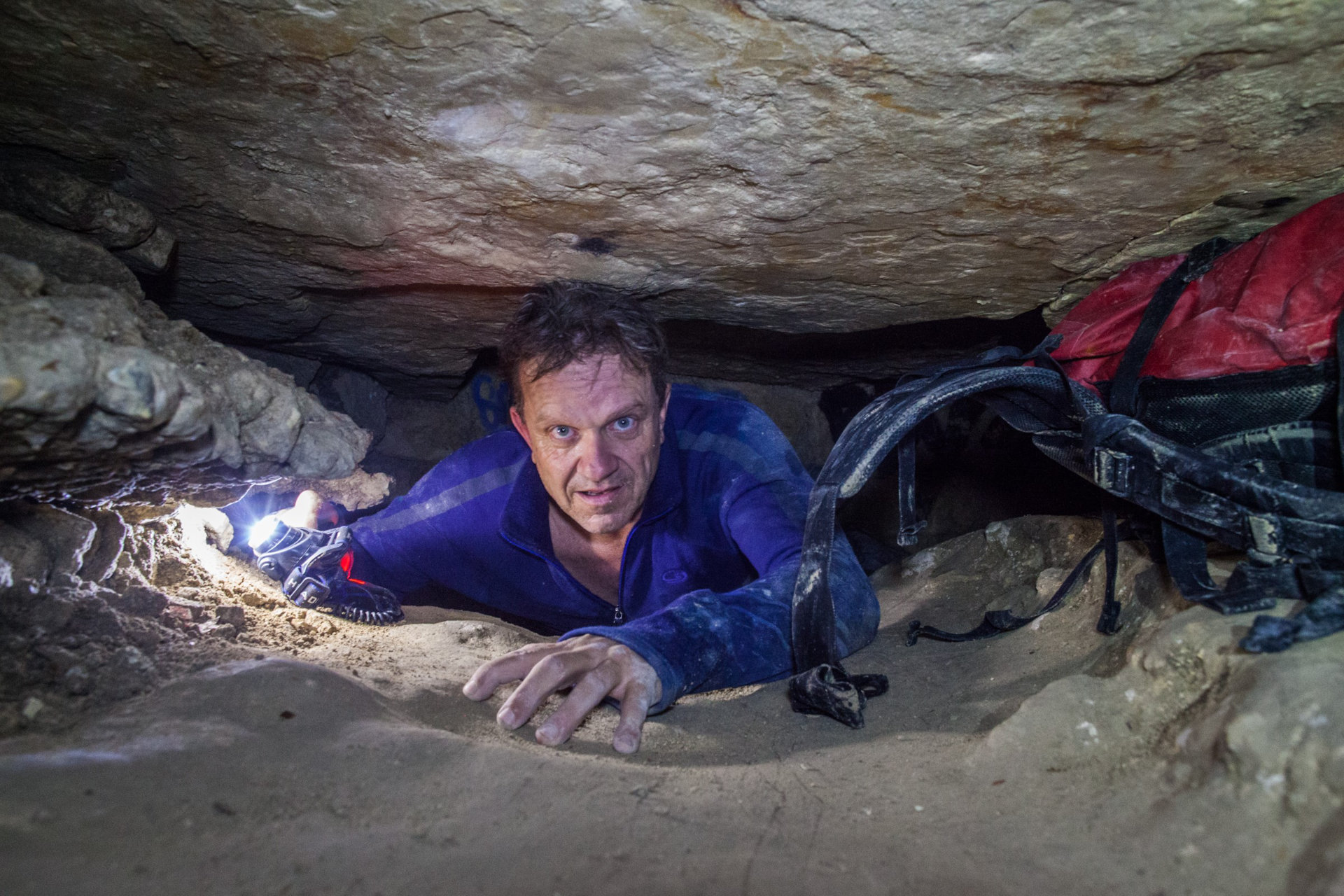 Author crawling through cave tunnel